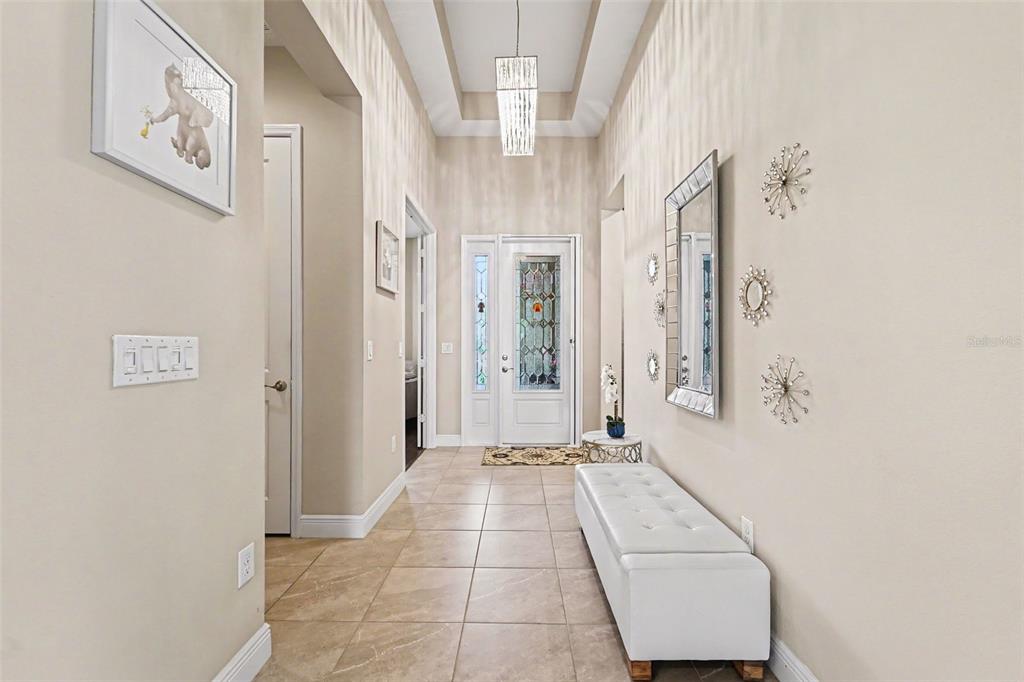 A bright entryway features tile flooring, a white tufted bench, and a decorative glass door — 30867 LINDENTREE DRIVE, WESLEY CHAPEL, FL