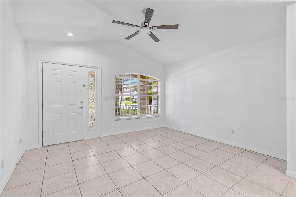 An empty room with white walls, tiled floors, a ceiling fan, and an arched window — 6115 SAND KEY LANE, WESLEY CHAPEL, FL