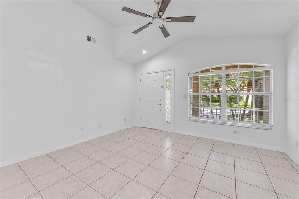 An empty room with white walls, tiled floors, a ceiling fan, and an arched window — 6115 SAND KEY LANE, WESLEY CHAPEL, FL
