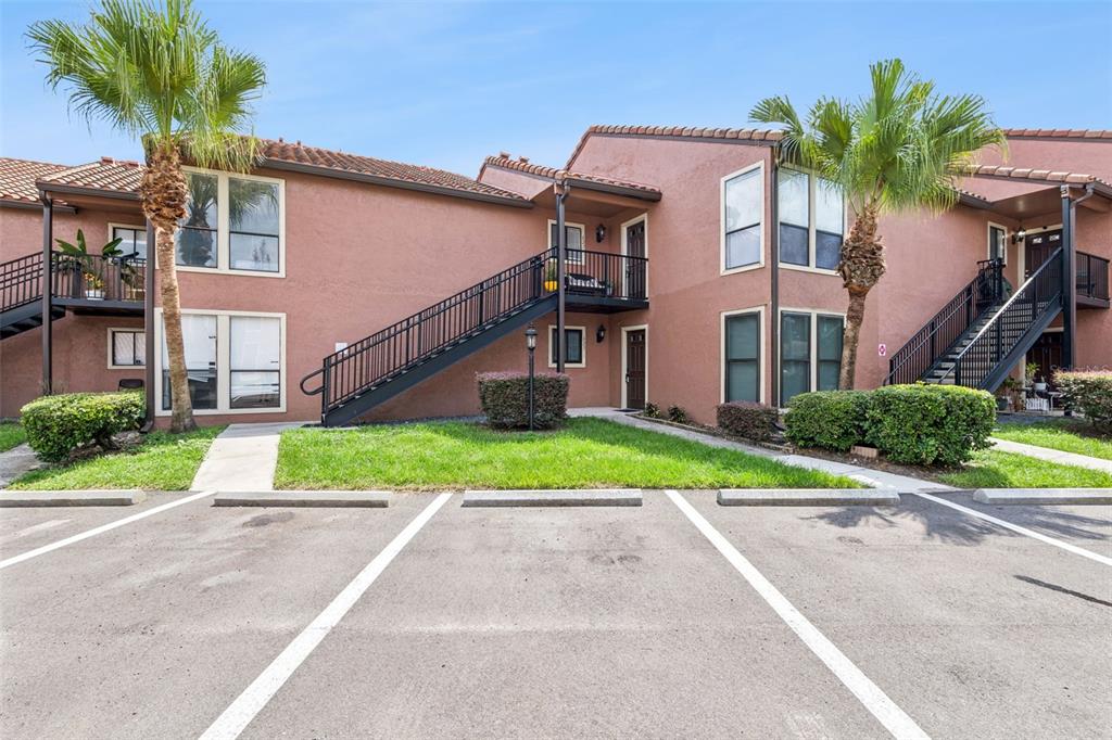 A two-story apartment building with stucco walls, external staircases, and palm trees in the foreground — 623 GRENADINE COURT UNIT 623, WINTER PARK, FL