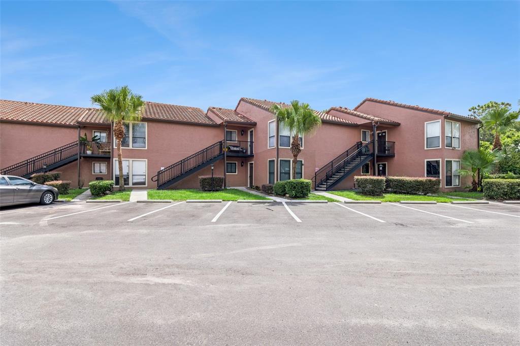 A two-story apartment building with stucco walls, tile roofs, and exterior staircases above a parking lot — 623 GRENADINE COURT UNIT 623, WINTER PARK, FL
