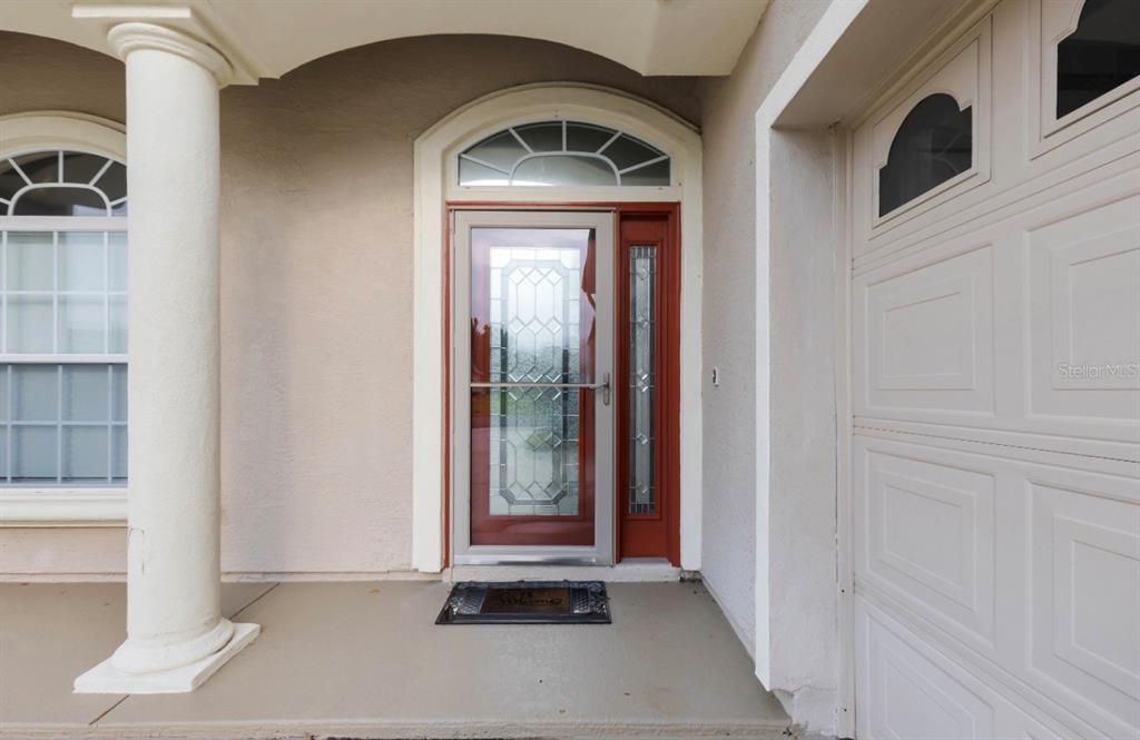 A front entryway features a red door with a glass storm door and a side light — 12139 SE 175TH LOOP, SUMMERFIELD, FL