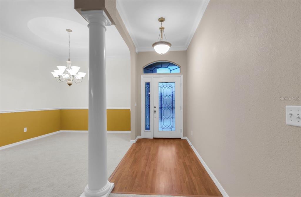 An entryway with wood flooring, a white column, and a front door with glass inserts — 12139 SE 175TH LOOP, SUMMERFIELD, FL
