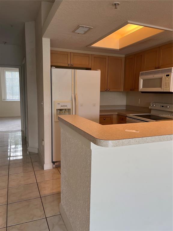 A kitchen with light wood cabinets, white appliances, and a breakfast bar — 116 BRENT CIRCLE, OLDSMAR, FL
