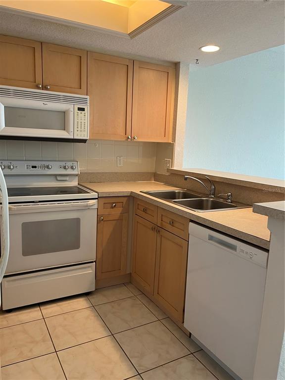 A kitchen features light wood cabinets, white appliances, and a double-basin stainless steel sink — 116 BRENT CIRCLE, OLDSMAR, FL