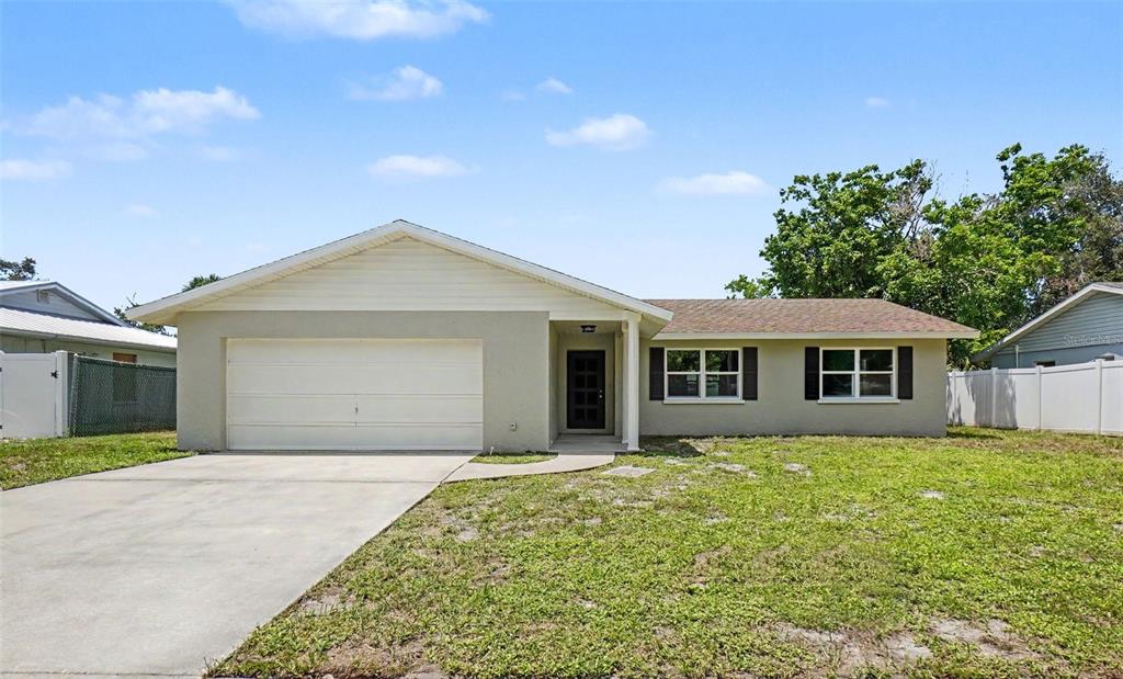 A single-story house with a beige exterior, a two-car garage, and a front lawn — 3410 50TH STREET W, BRADENTON, FL