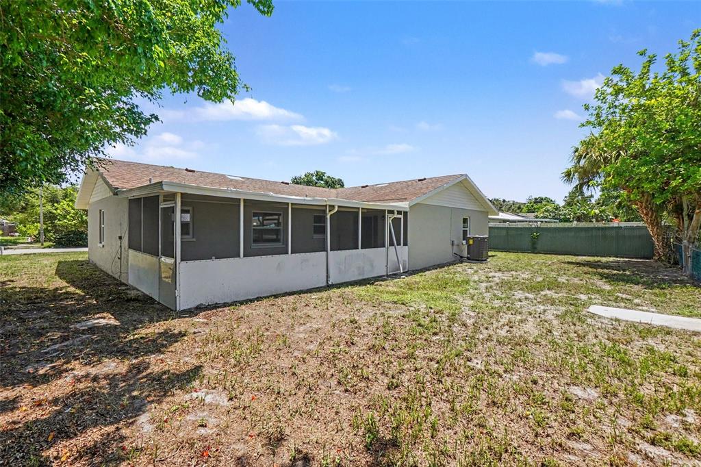 The exterior of a single-story house features a screened-in porch and a large backyard — 3410 50TH STREET W, BRADENTON, FL