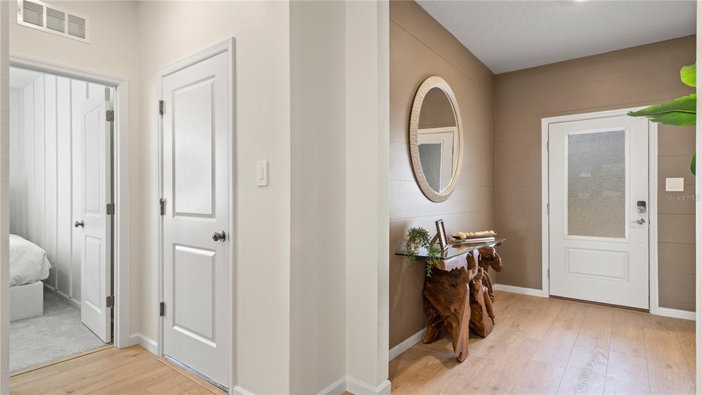 An entryway features light wood flooring, a brown accent wall, a mirror, and a console table — 770 TUNDRA LOOP, GROVELAND, FL