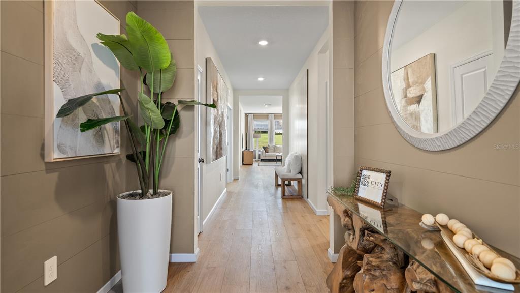 A hallway with light wood floors, a tall potted plant, and a rustic wood console table — 770 TUNDRA LOOP, GROVELAND, FL