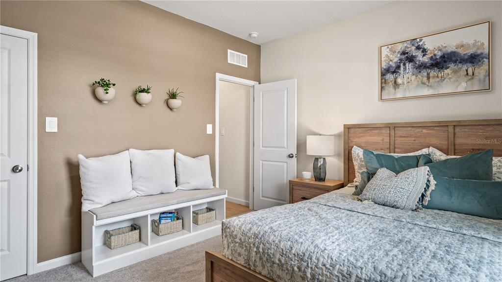 A bedroom features a wooden bed frame, a white storage bench, and wall-mounted planters — 770 TUNDRA LOOP, GROVELAND, FL