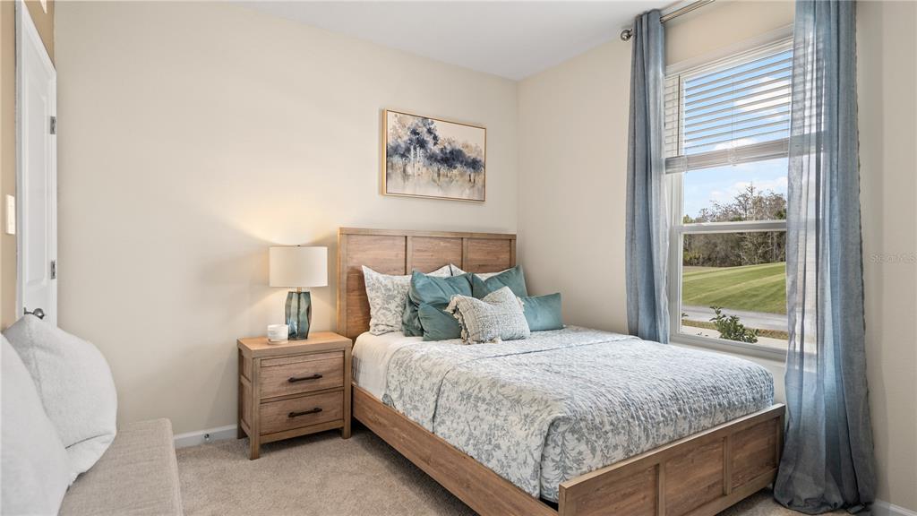 A bedroom features a wooden bed frame, a matching nightstand with a lamp, and a window — 770 TUNDRA LOOP, GROVELAND, FL