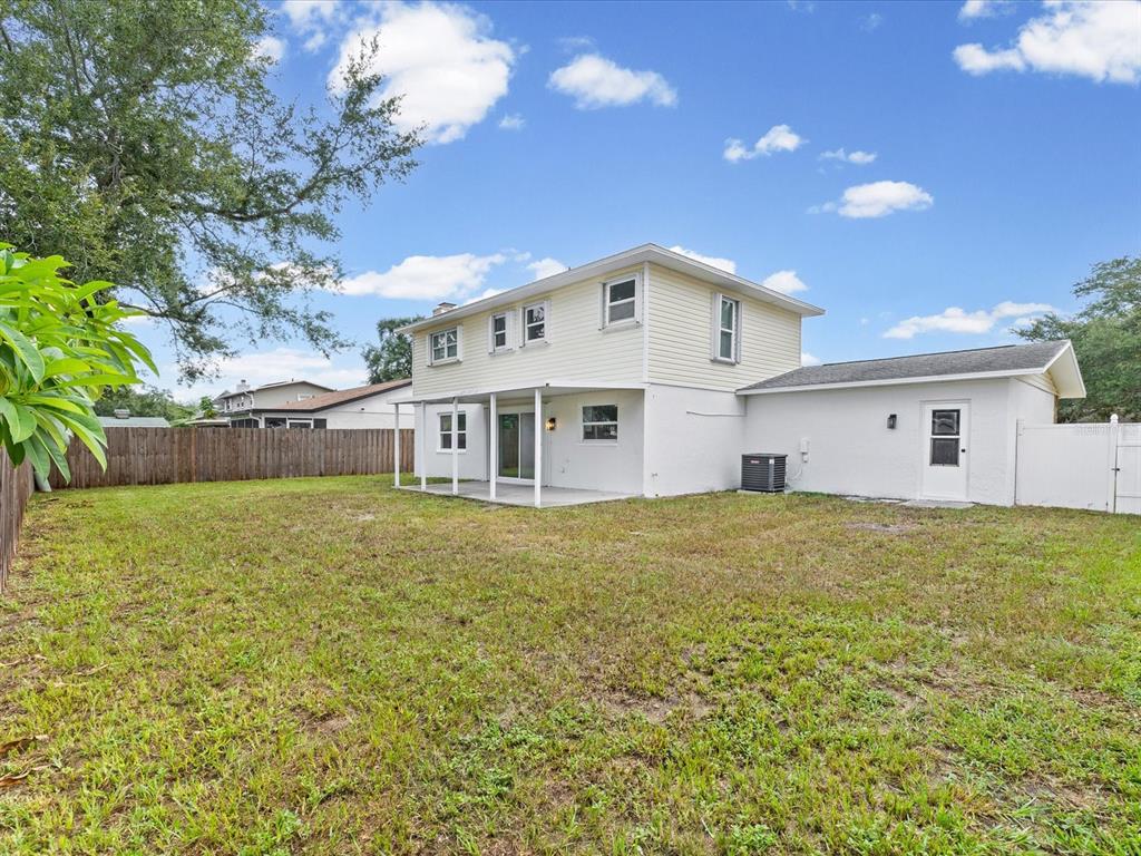 The exterior of a two-story house features a backyard, a patio, and a white fence — 1972 LANSING DRIVE, CLEARWATER, FL