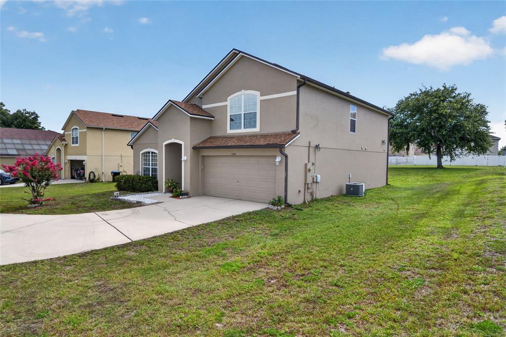 A two-story suburban house with a tan stucco exterior, a two-car garage, and a lawn — 5306 RABBIT RIDGE TRAIL, ORLANDO, FL