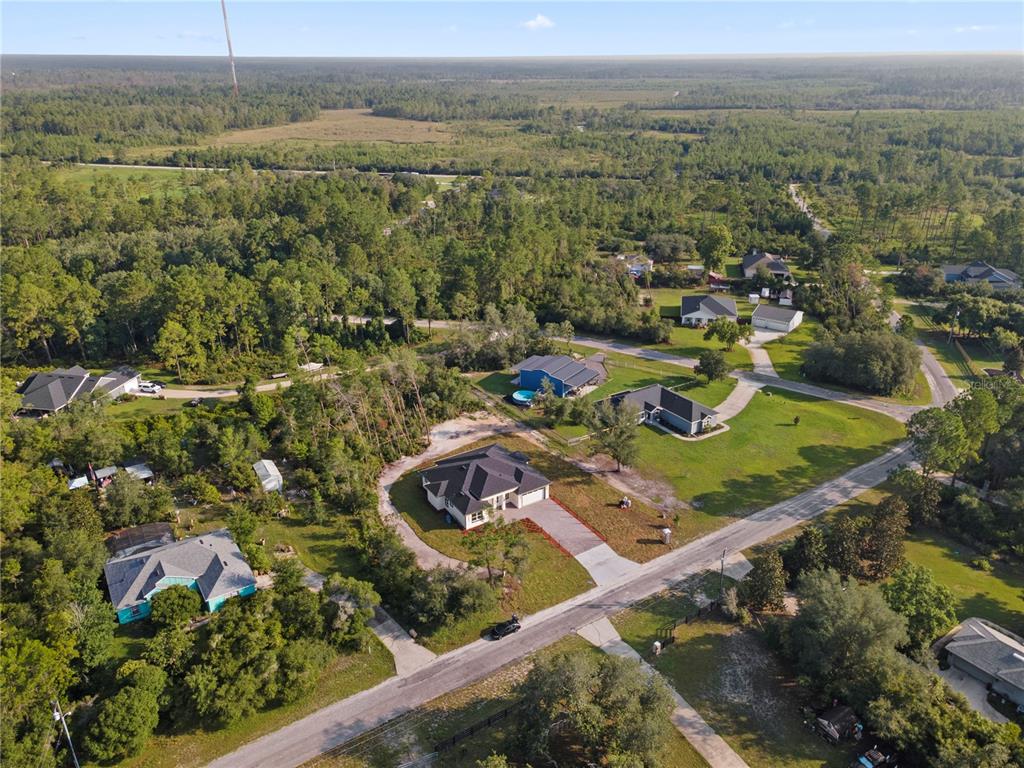 An aerial view shows a new single-story house with a paved driveway and surrounding woods — 30643 APRICOT AVENUE, EUSTIS, FL