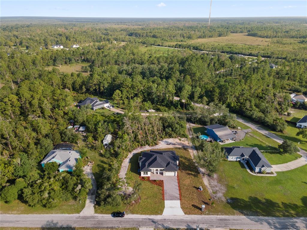 An aerial view shows several houses surrounded by trees and grassy lots near a road — 30643 APRICOT AVENUE, EUSTIS, FL