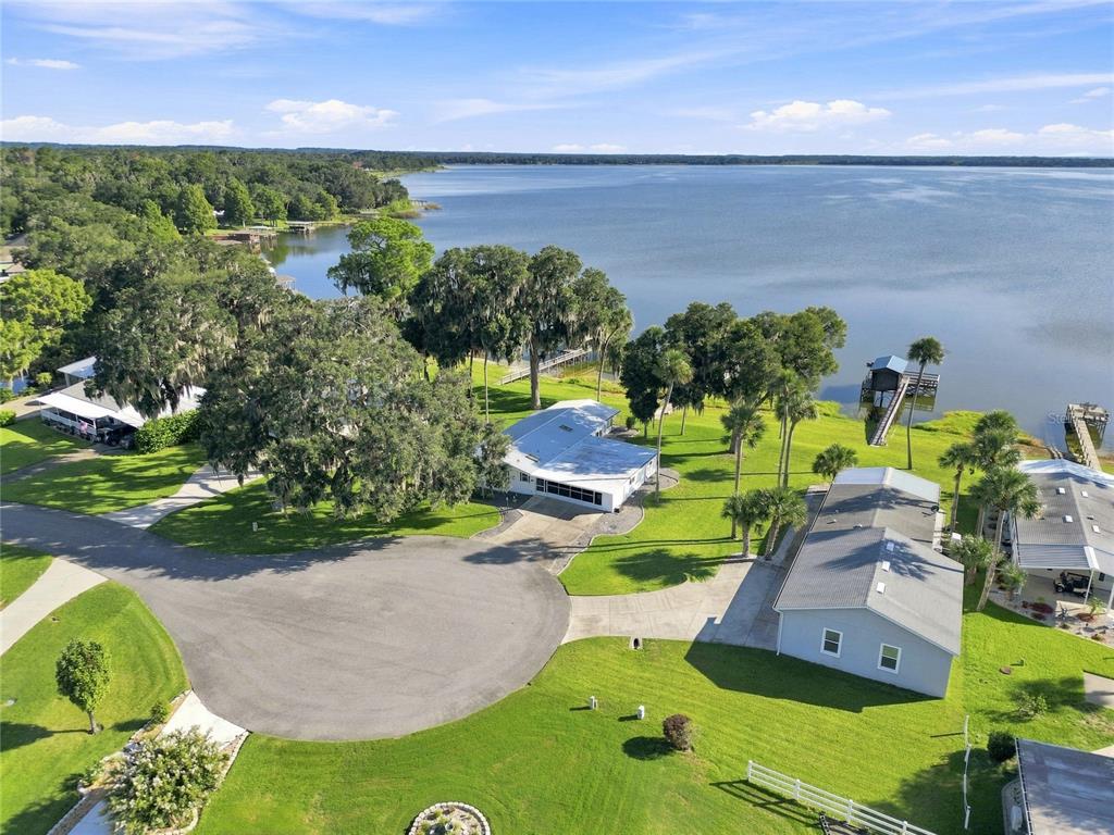 An aerial view shows a waterfront house with a large lawn and private boat dock — 38310 LANGLOIS PLACE, LEESBURG, FL