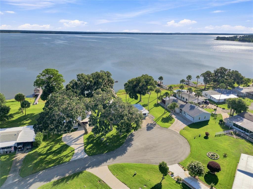 An aerial view shows several houses on a grassy lot bordering a large lake — 38310 LANGLOIS PLACE, LEESBURG, FL