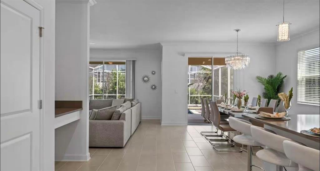An open-concept living and dining area features tile flooring, a crystal chandelier, and sliding doors — 8907 PLAY THROUGH DRIVE, DAVENPORT, FL