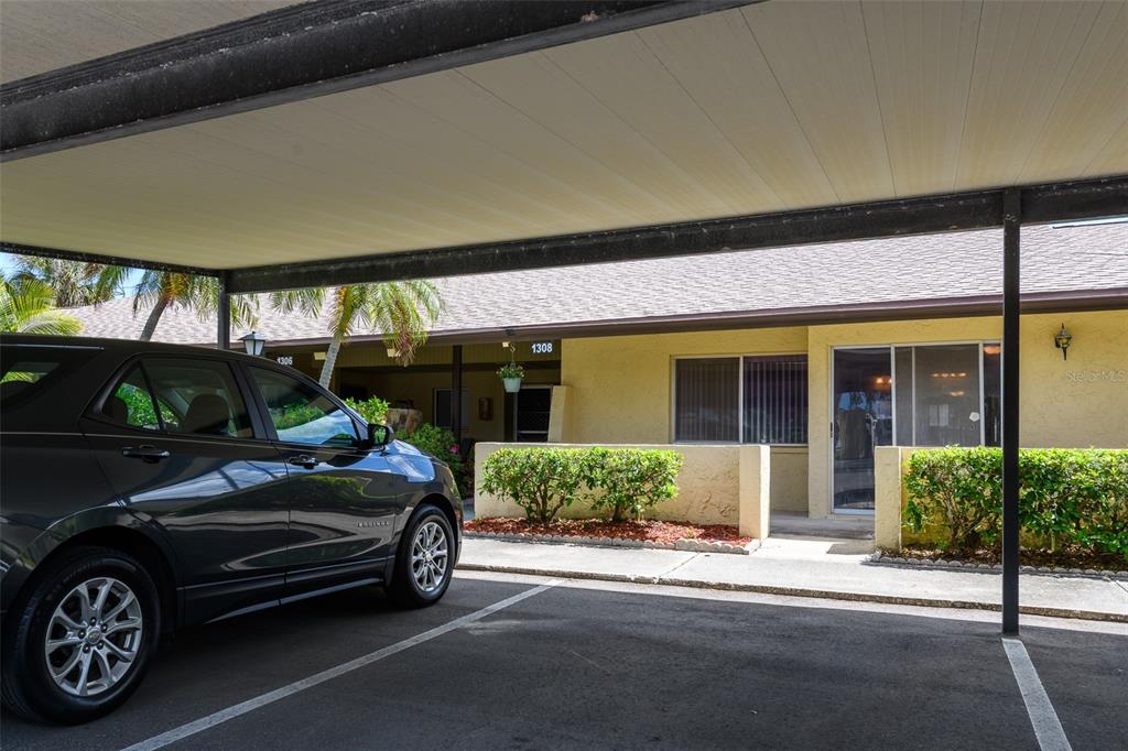 A car is parked under a carport in front of a single-story residential building — 1308 13TH CIRCLE SE, LARGO, FL