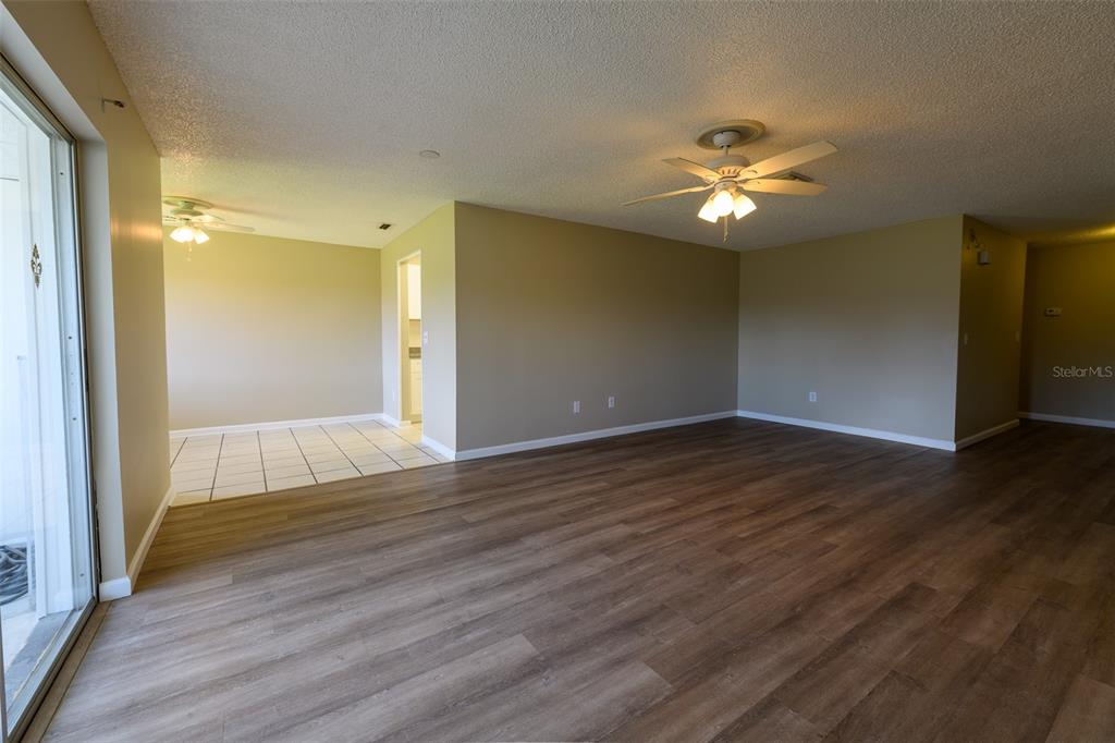 An open living area features wood-look flooring, a ceiling fan, and an adjacent tiled space — 1308 13TH CIRCLE SE, LARGO, FL