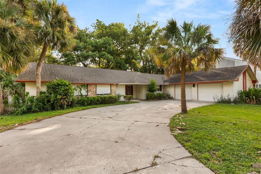 A single-story house with a concrete driveway, two-car garage, and palm trees in the yard — 3889 N LAKE ORLANDO PARKWAY, ORLANDO, FL