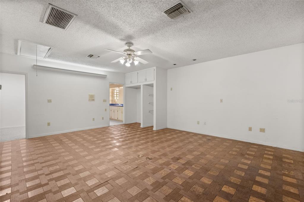A spacious room features a parquet wood floor, a ceiling fan, and white walls — 3889 N LAKE ORLANDO PARKWAY, ORLANDO, FL