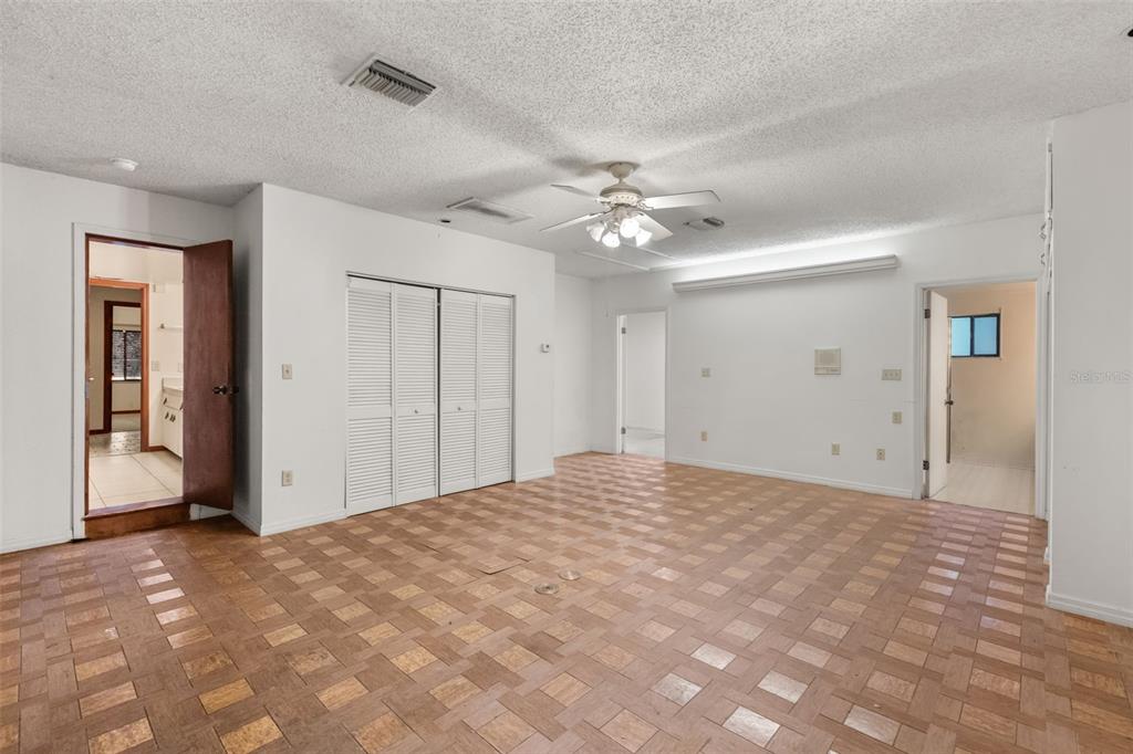 A room with parquet flooring, white walls, a ceiling fan, and multiple doorways — 3889 N LAKE ORLANDO PARKWAY, ORLANDO, FL