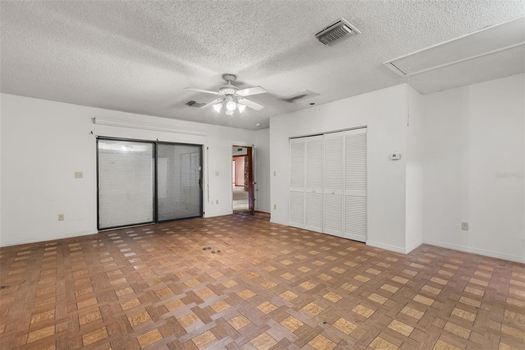 An empty room features parquet wood flooring, a ceiling fan, and white louvered closet doors — 3889 N LAKE ORLANDO PARKWAY, ORLANDO, FL