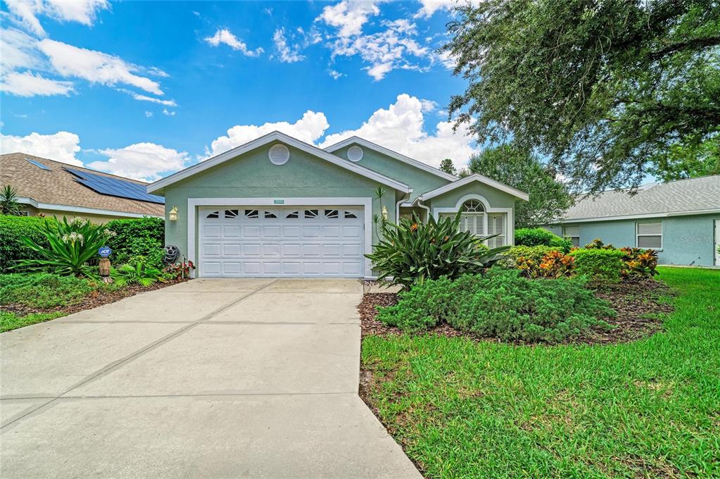 A single-story house with a white garage door, green siding, and a concrete driveway — 7488 ELEANOR CIRCLE, SARASOTA, FL