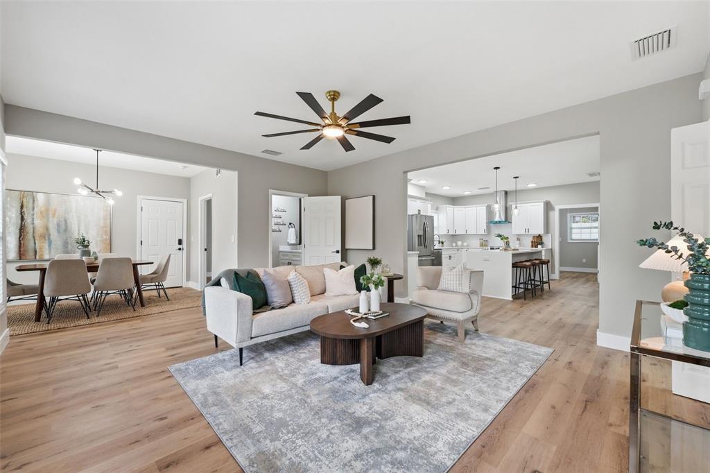 An open-concept living room features light wood floors, a modern ceiling fan, and neutral decor — 15 E LAUREL STREET, APOPKA, FL