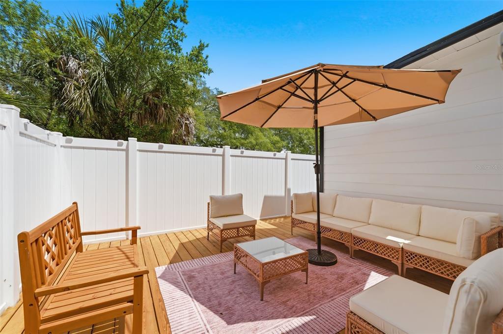 A wooden deck features patio furniture, a tan umbrella, and a white privacy fence — 15 E LAUREL STREET, APOPKA, FL