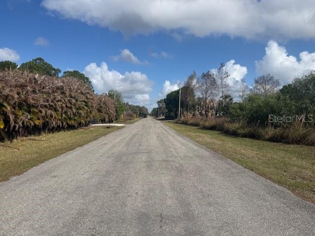A paved road stretches into the distance between dense vegetation and trees under a blue sky — 17892 75TH PLACE N, LOXAHATCHEE, FL