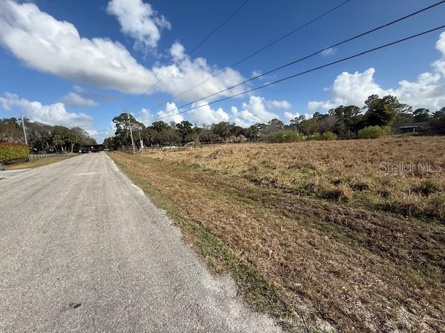 A gravel road runs alongside a large, undeveloped grassy lot under a blue sky — 17892 75TH PLACE N, LOXAHATCHEE, FL