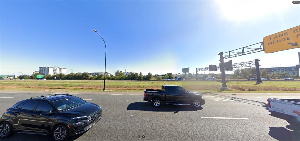 A black pickup truck and a black SUV drive on a highway near a merge sign — I-4, DAVENPORT, FL