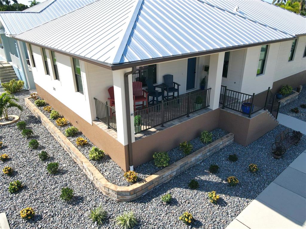 An elevated porch with a metal roof overlooks a gravel yard with small shrubs — 301 GOLDSTEIN STREET, PUNTA GORDA, FL