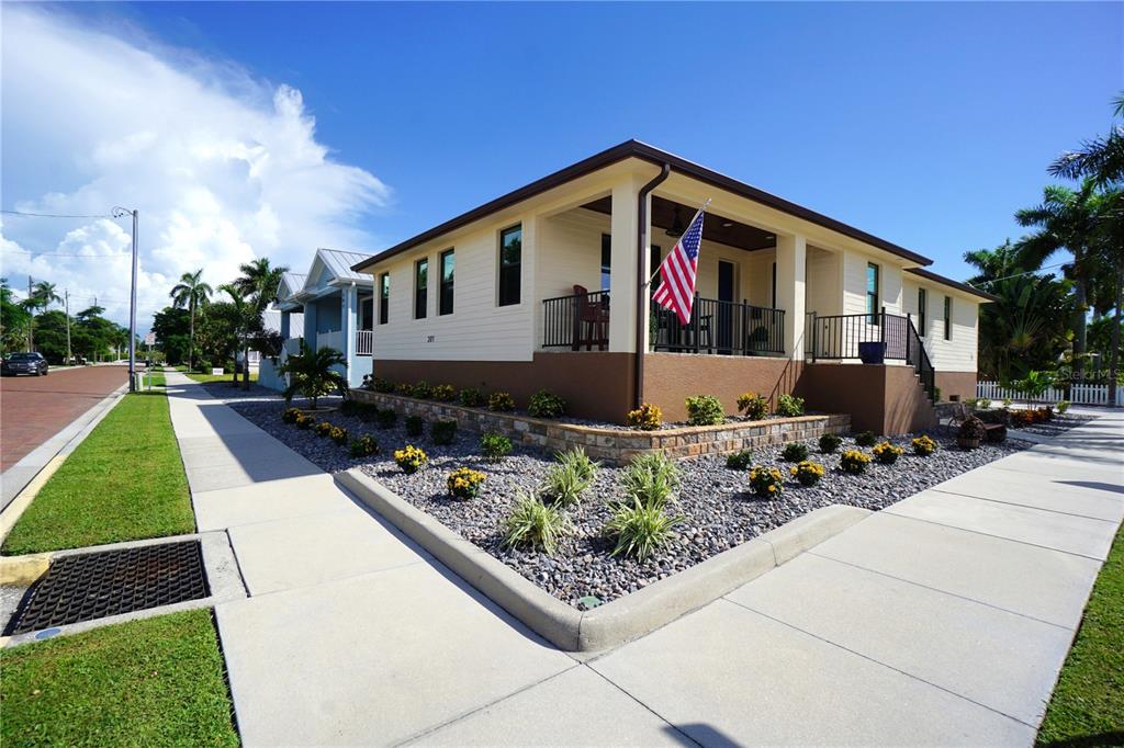 A single-story house with a covered porch, American flag, and landscaped rock garden — 301 GOLDSTEIN STREET, PUNTA GORDA, FL