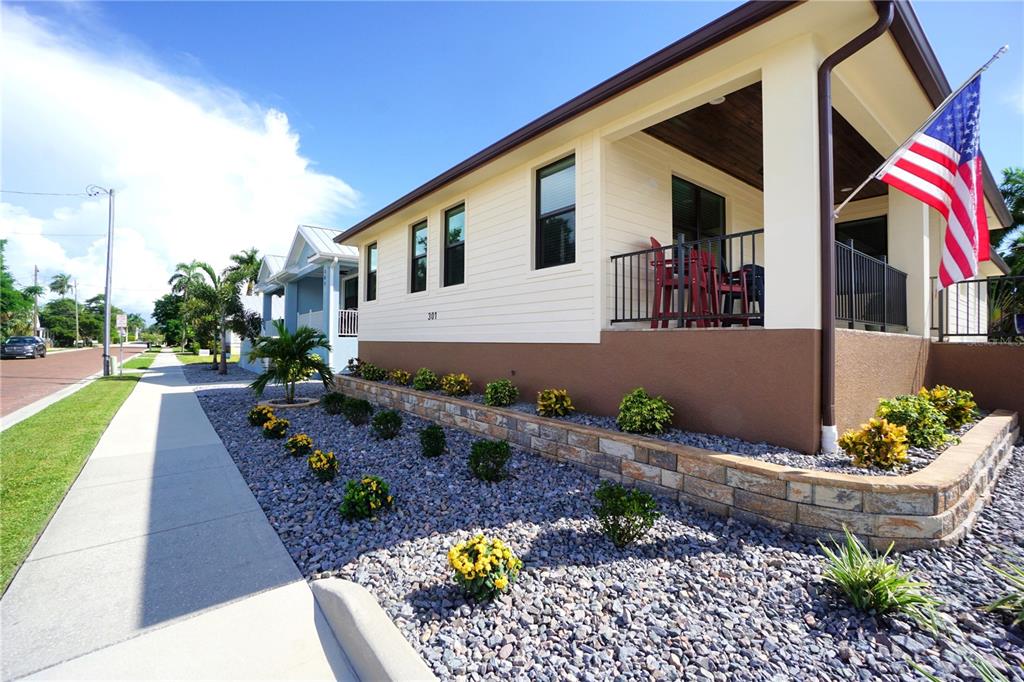 A low-angle exterior view of a house with a stone retaining wall and landscaping — 301 GOLDSTEIN STREET, PUNTA GORDA, FL