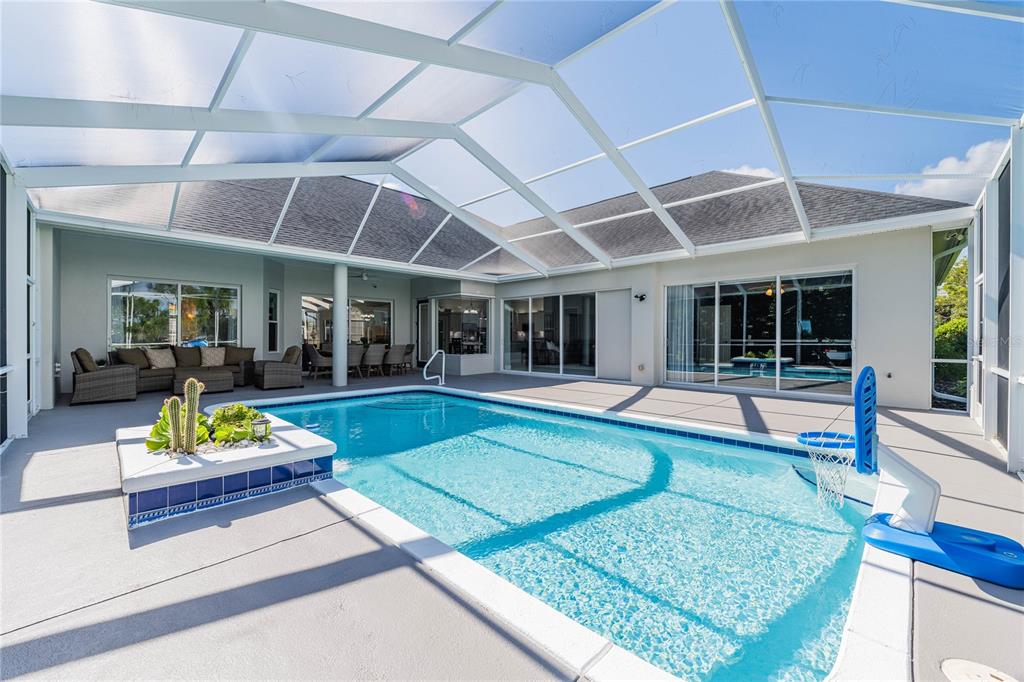 A screened-in patio features a swimming pool, a basketball hoop, and outdoor lounge furniture — 1221 VISTA HILLS DRIVE, LAKELAND, FL