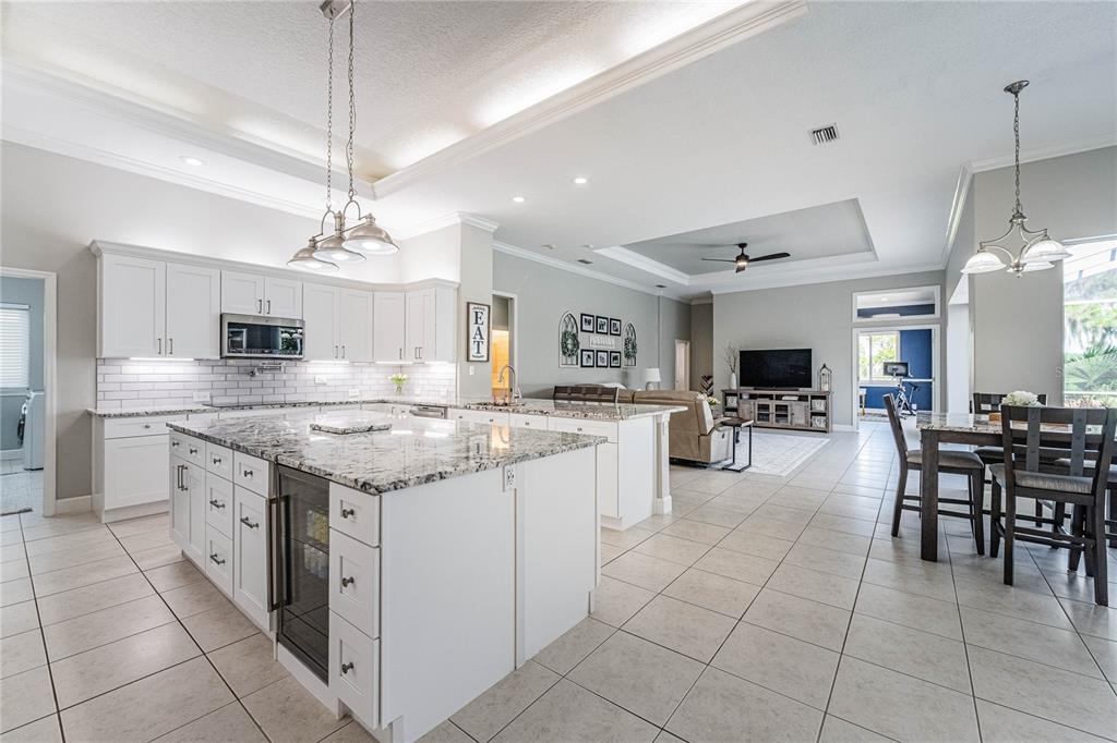 A bright, open-concept kitchen with white cabinetry, granite countertops, and an island with a cooler — 1221 VISTA HILLS DRIVE, LAKELAND, FL
