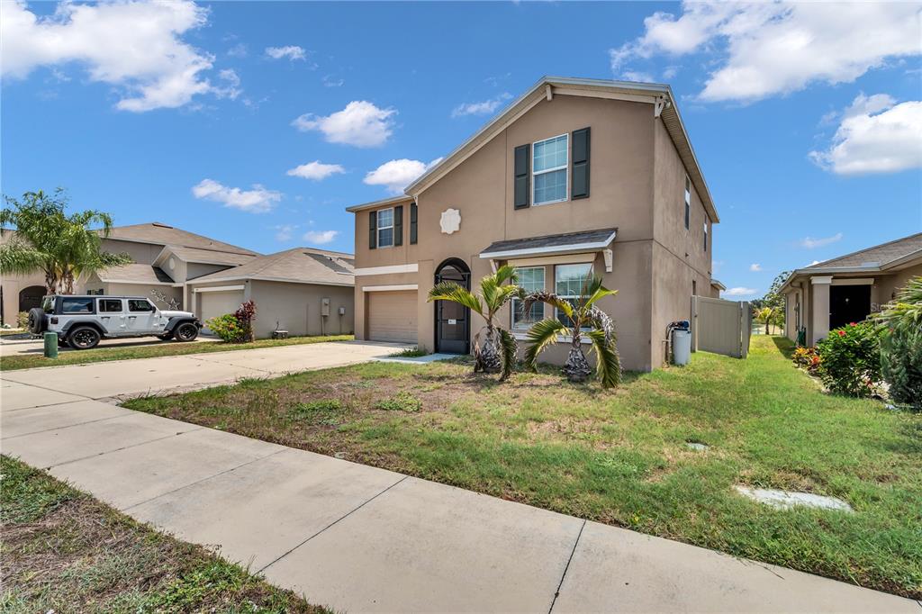 A two-story tan stucco house with a garage and a front yard under a sky — 1739 BROAD WINGED HAWK DRIVE, RUSKIN, FL