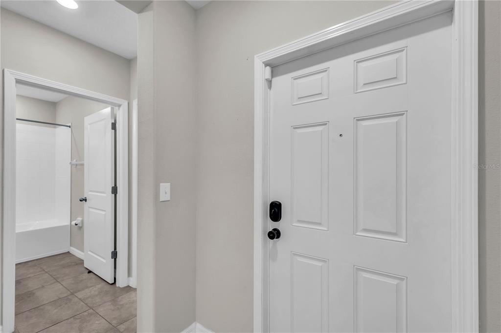 A white door with a smart lock stands next to a bathroom doorway — 1739 BROAD WINGED HAWK DRIVE, RUSKIN, FL