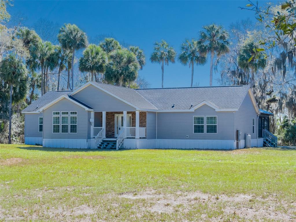 A gray, single-story manufactured home with a front porch sits on a grassy lot — 17482 SE 34TH LANE, OCKLAWAHA, FL