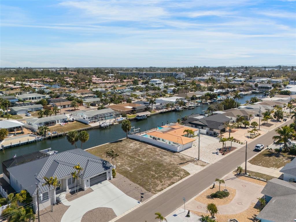 An aerial view shows a residential neighborhood with houses along a canal and a vacant lot — 4007 COCONUT TERRACE, BRADENTON, FL