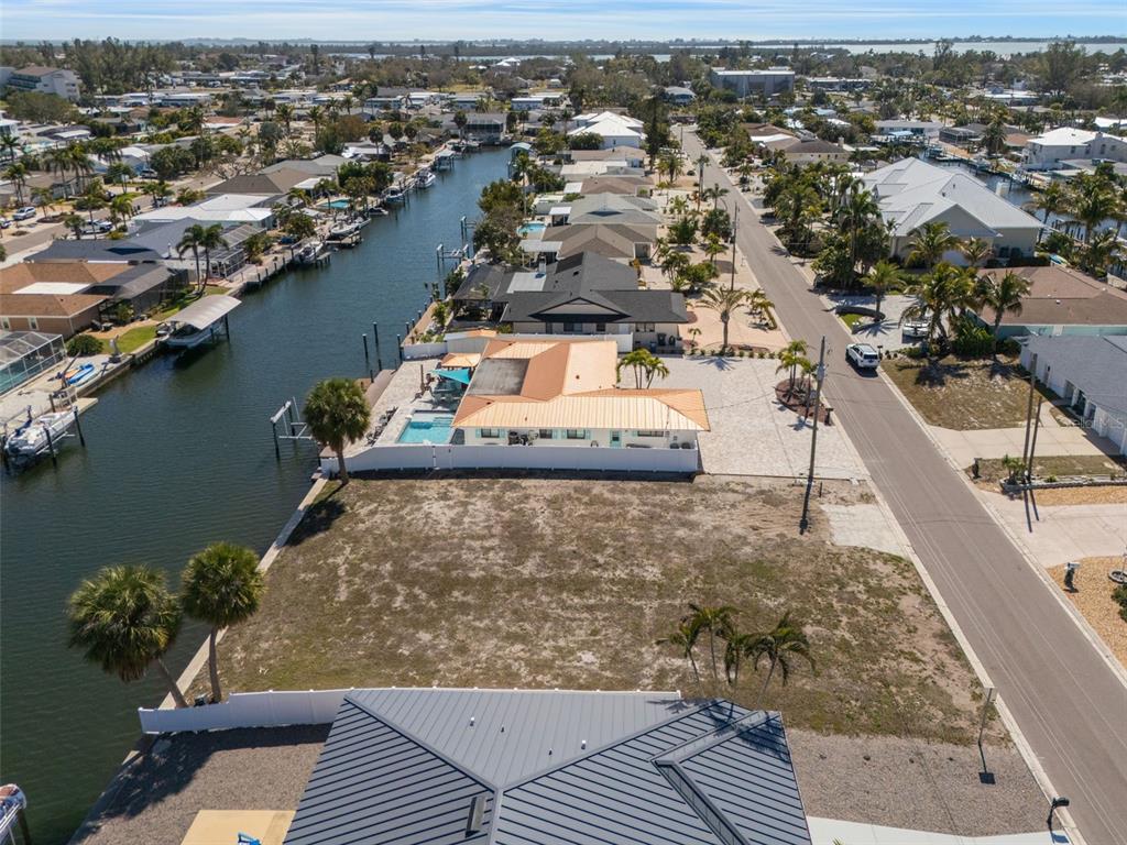An aerial view shows a vacant waterfront lot next to a house with a pool — 4007 COCONUT TERRACE, BRADENTON, FL