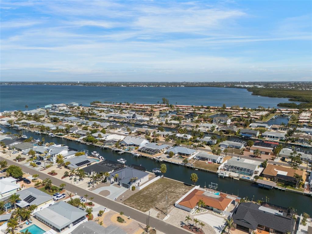 An aerial view shows waterfront houses along canals leading to a large bay — 4007 COCONUT TERRACE, BRADENTON, FL