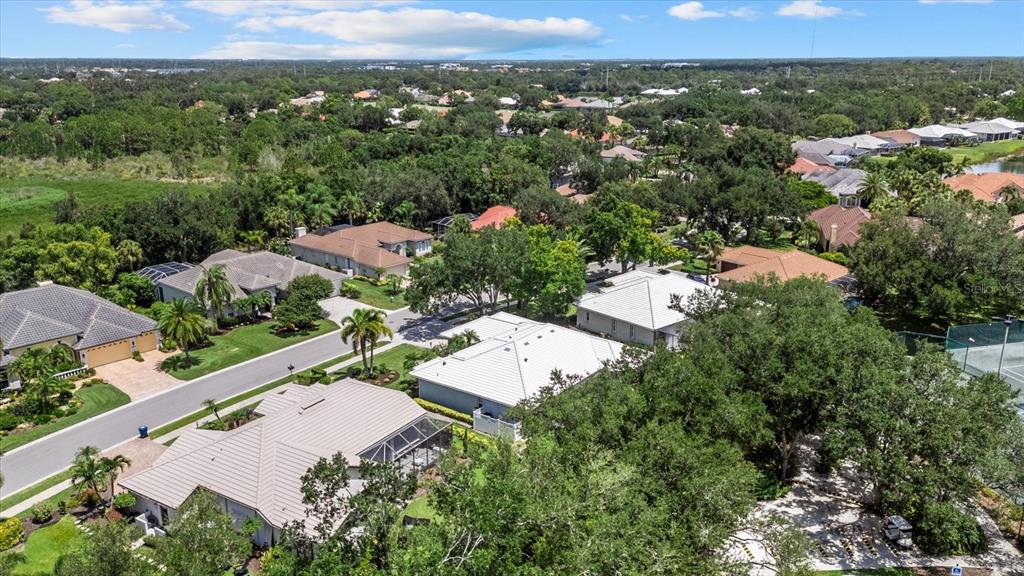 An aerial view shows several suburban houses with tiled roofs surrounded by trees and landscaping — 288 VENICE GOLF CLUB DRIVE, VENICE, FL