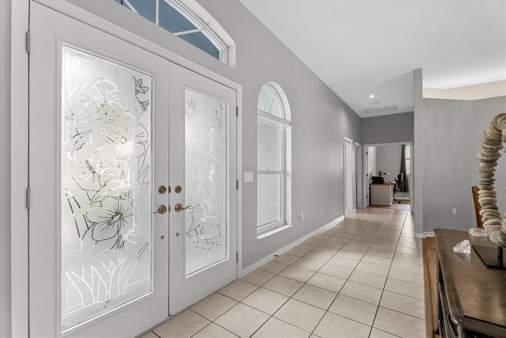 A bright entryway features double glass-paneled doors, arched windows, and light-colored tile flooring — 288 VENICE GOLF CLUB DRIVE, VENICE, FL