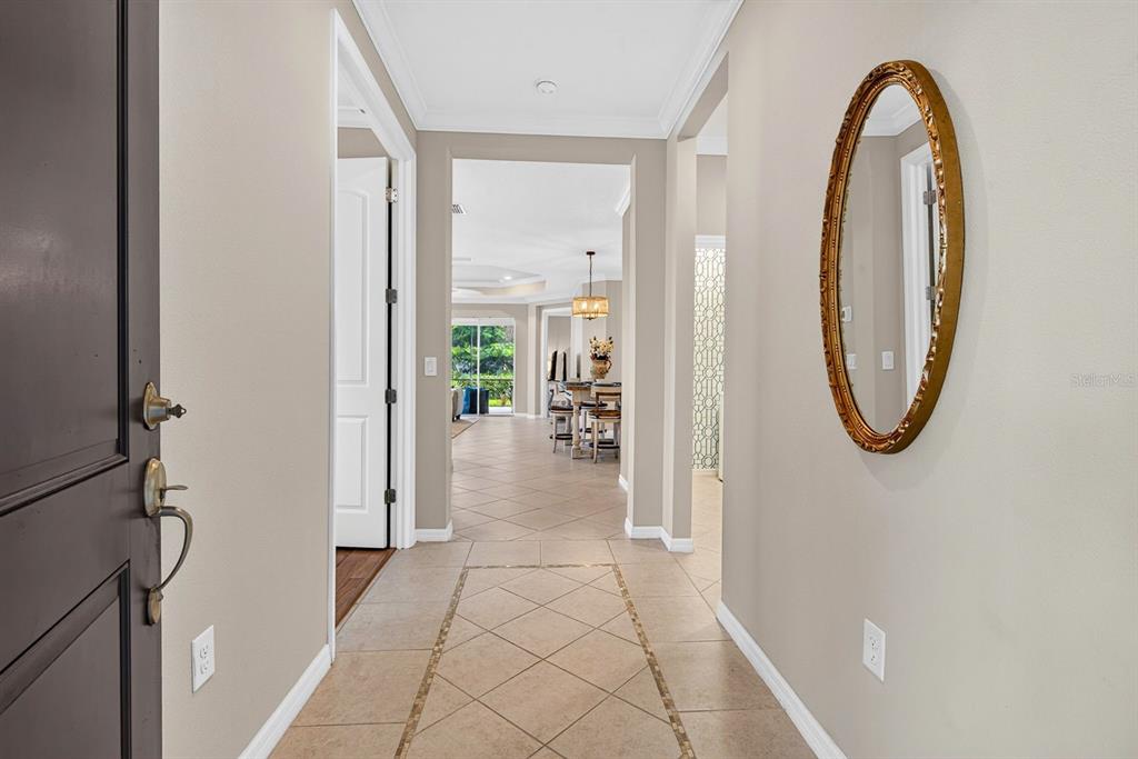 A tiled entryway leads into a bright living area with a gold-framed oval wall mirror — 7108 PLAYA BELLA DRIVE, BRADENTON, FL