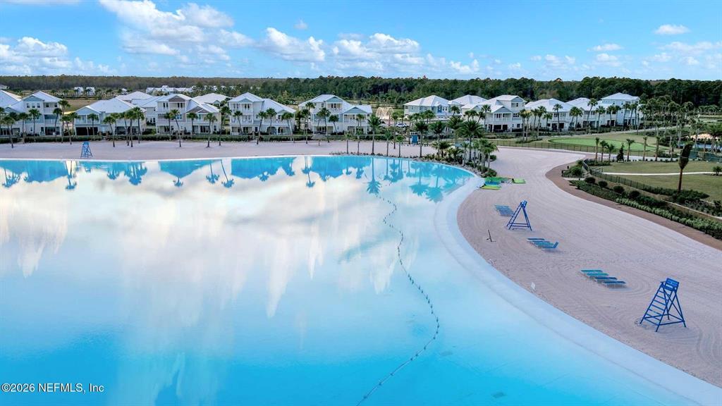 An aerial view shows a large turquoise lagoon with a sandy beach and surrounding houses — 244 RUM RUNNER WAY, ST JOHNS, FL