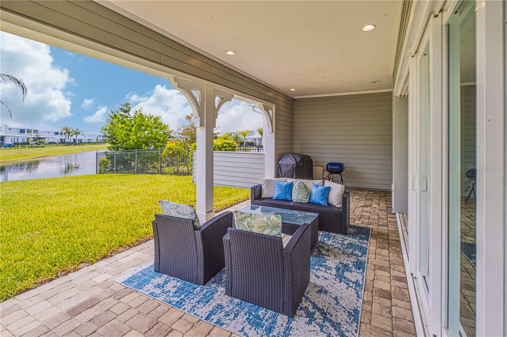 A covered patio with outdoor furniture overlooks a grassy lawn and a small lake — 244 RUM RUNNER WAY, ST JOHNS, FL